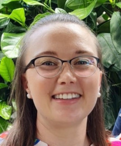 Fair skinned woman, brunette hair, wearing glasses, stripped blouse