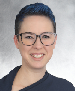 Fair skinned woman, short brunette hair, wearing glasses and navy top